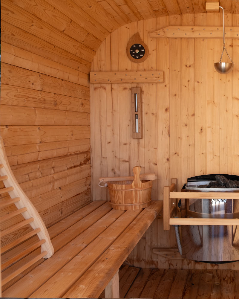 Warm, minimalist timber sauna interior attached to a private training facility, soft low lighting, folded towels on a bench, calm and premium atmosphere, editorial wellness photography